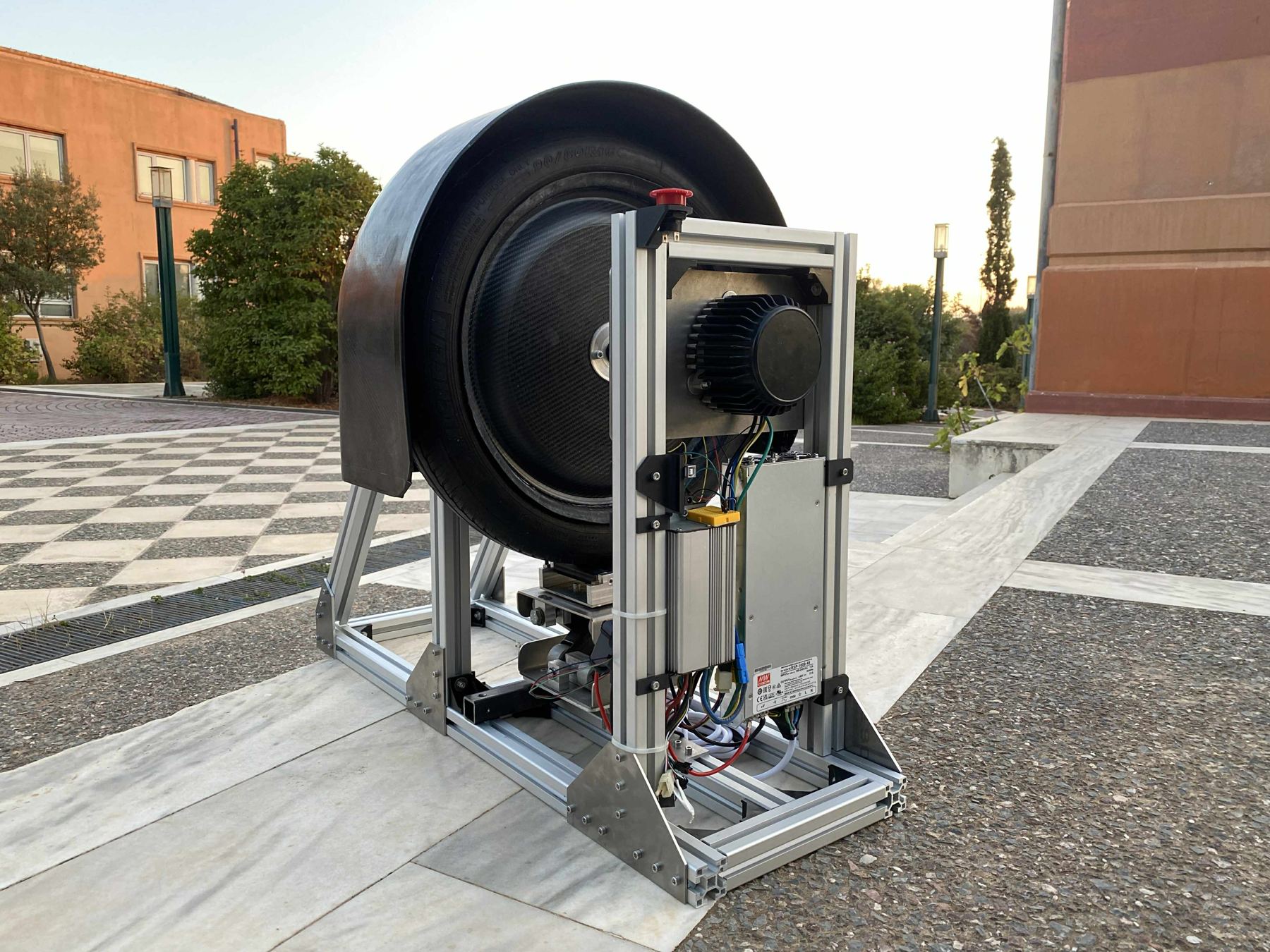 The assembled wheel test bench: T-slot aluminum frame, wheel mounted for testing, motor, and electronics enclosure with E-STOP button
